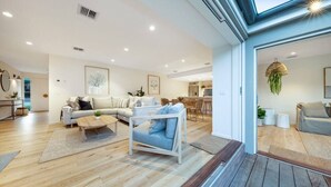 A spacious living area with a sofa set, a coffee table, and a chair. There is a dining area with chairs and a table in the background. - Casa del Sol | Indoor Fireplace & Heated Pool (Sorrento)