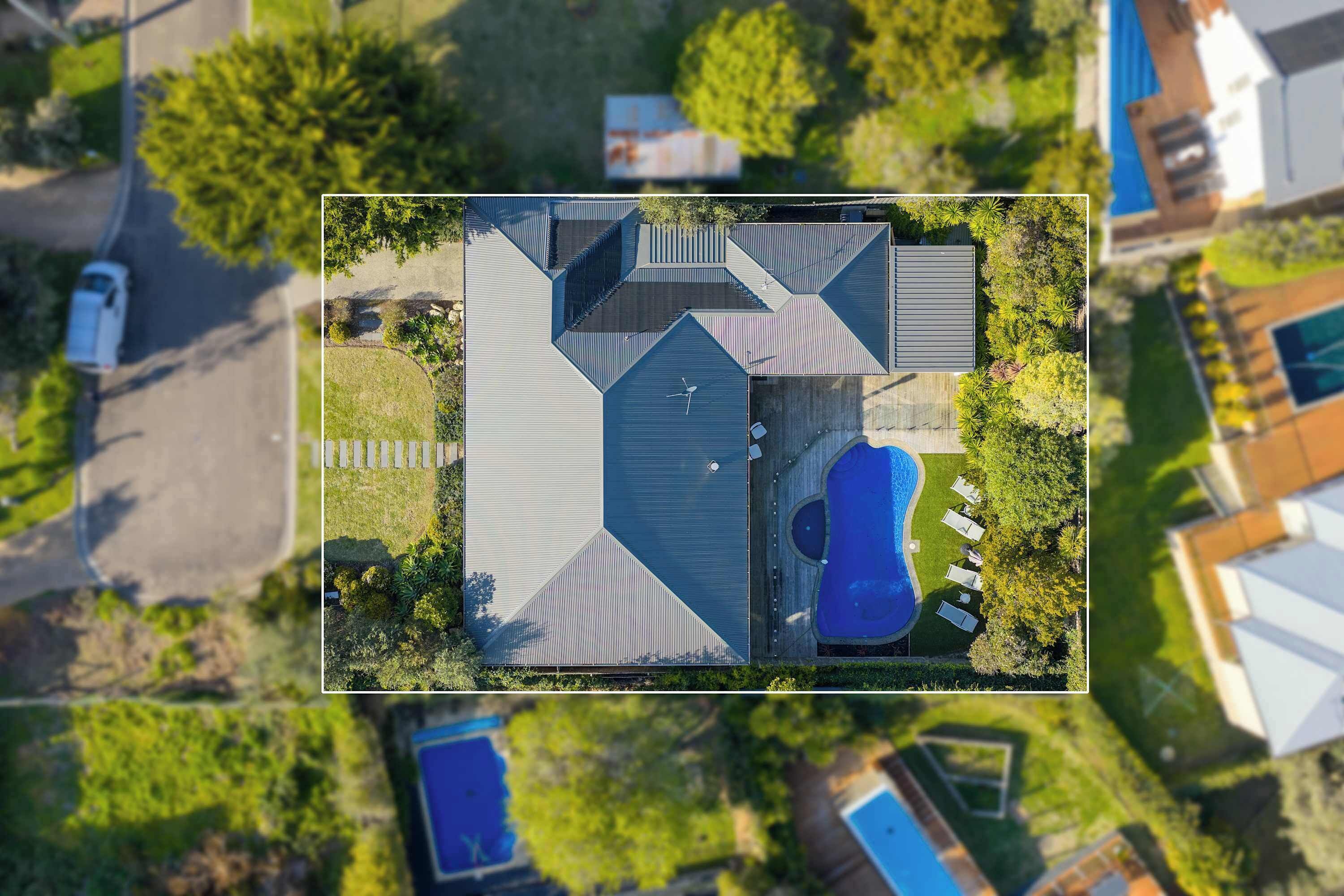Una vista aerea di una casa moderna con piscina, garage e prato curato.