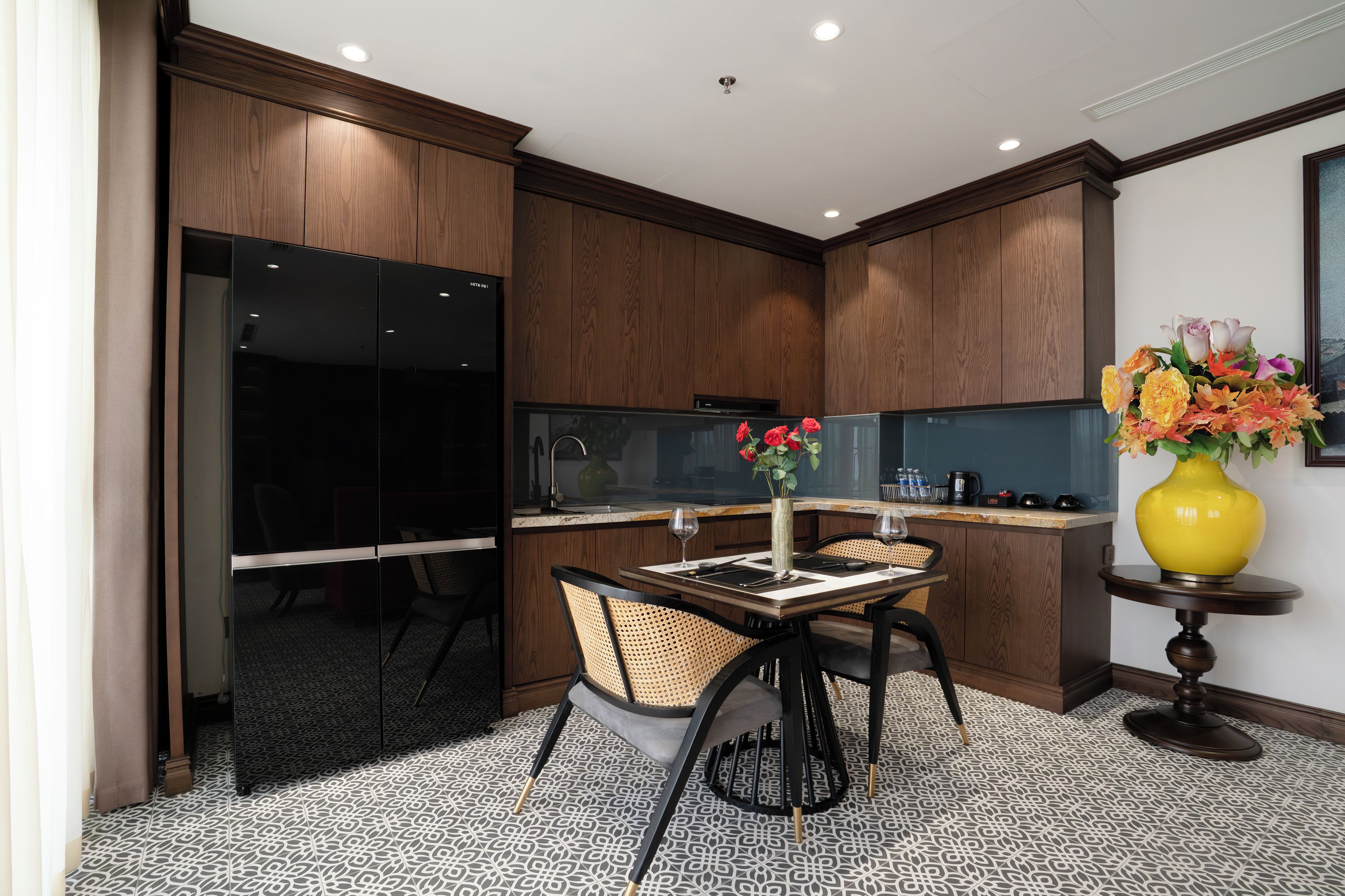 A modern kitchen with wooden cabinets, a dining area with a table and chairs, and a vase with flowers on a side table.