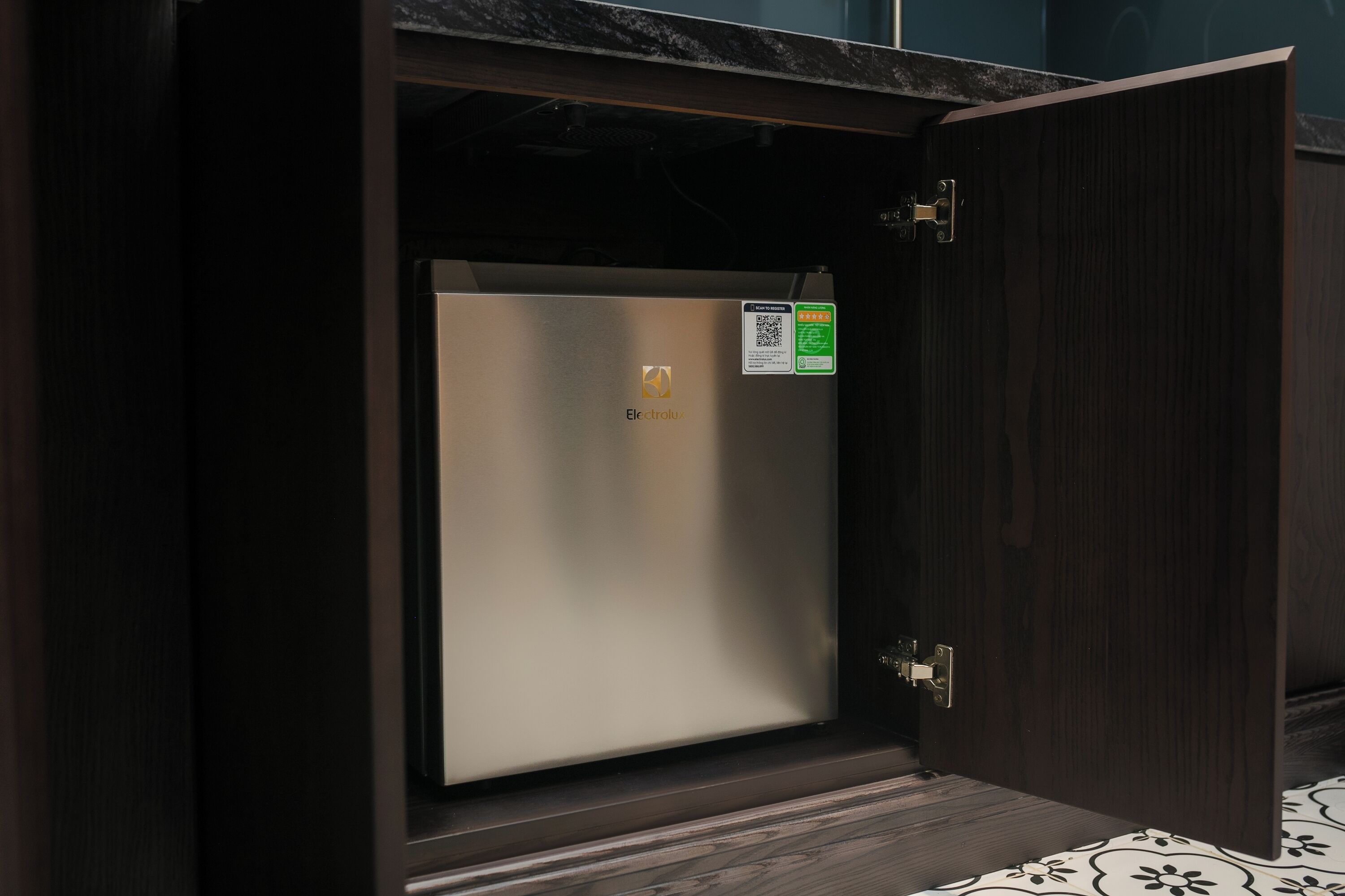 A compact, dark wooden cabinet with a metallic appliance inside, possibly a refrigerator, and a QR code on the door.