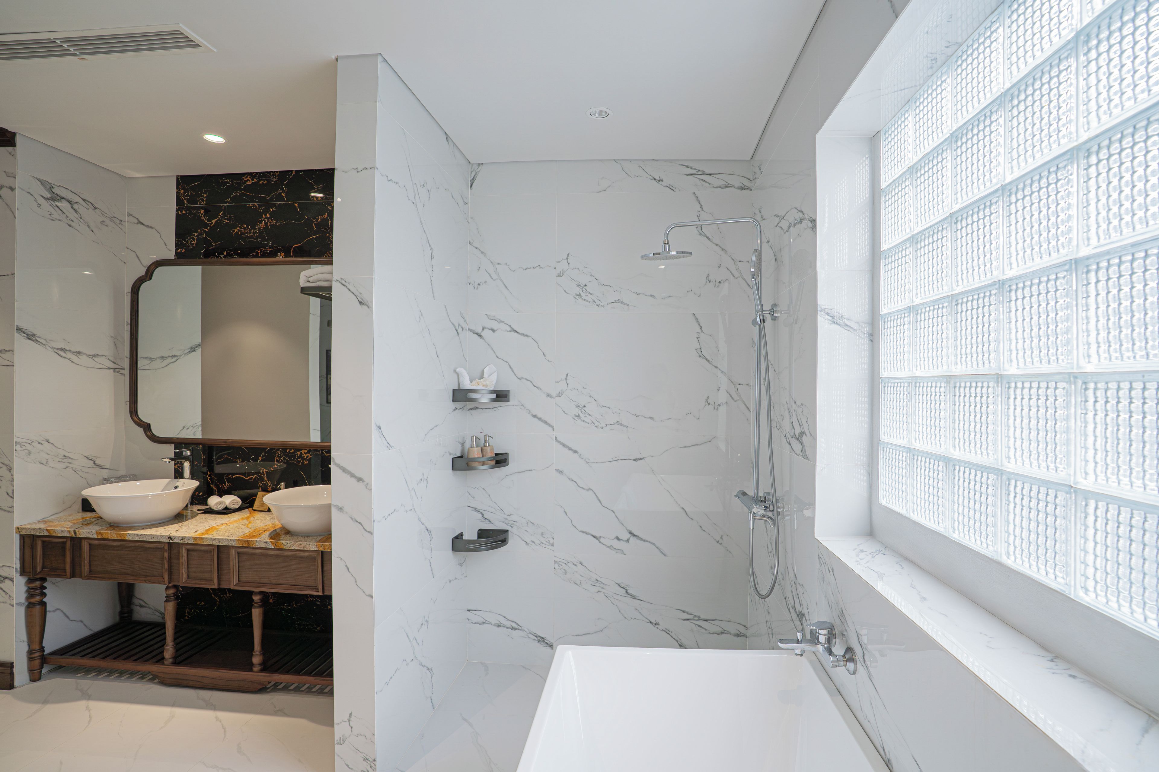 A modern bathroom with a large mirror, two sinks, a shower, and a window with a grid pattern.