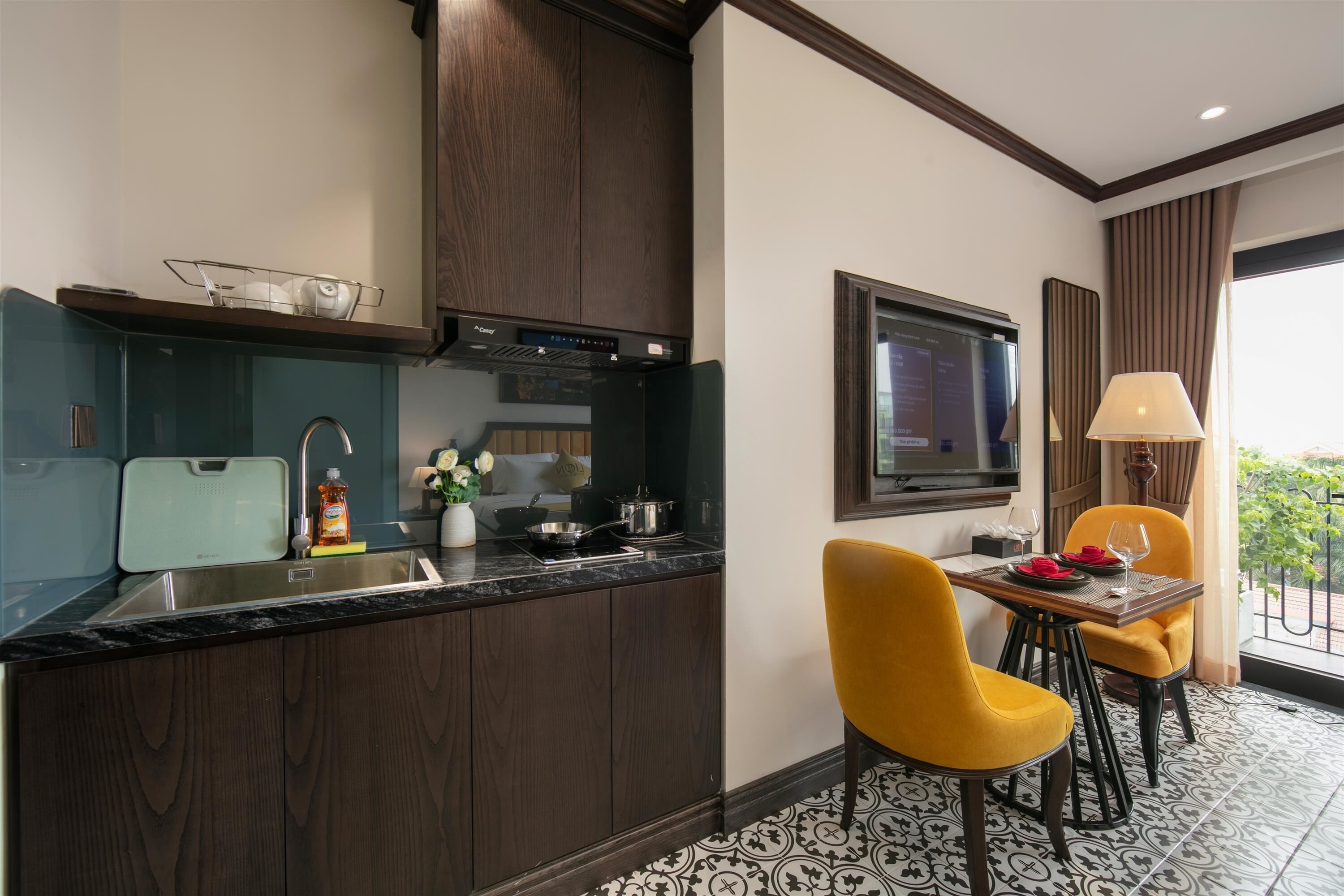 Una cocina moderna con armarios de madera oscura, estufa integrada y un comedor con sillas amarillas y una mesa.