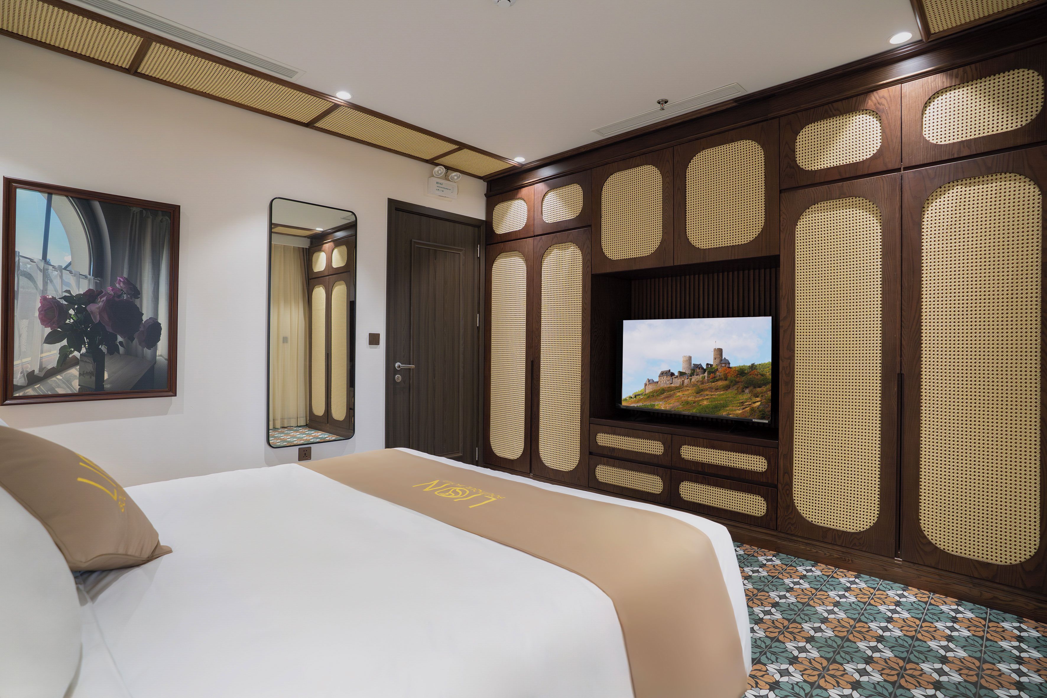 Een hotelkamer met een bed, een televisie, een spiegel en een decoratief paneel aan de muur.