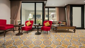 A room with red chairs, a small table, and a sofa with a decorative pillow. - Westlake Lion Boutique Studio & Spa (Hanoi)