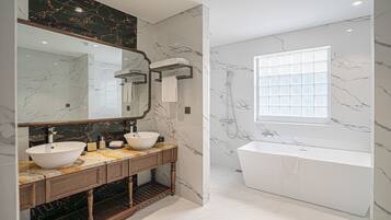 Une salle de bain moderne avec un grand miroir, deux lavabos, une baignoire et une fenêtre.