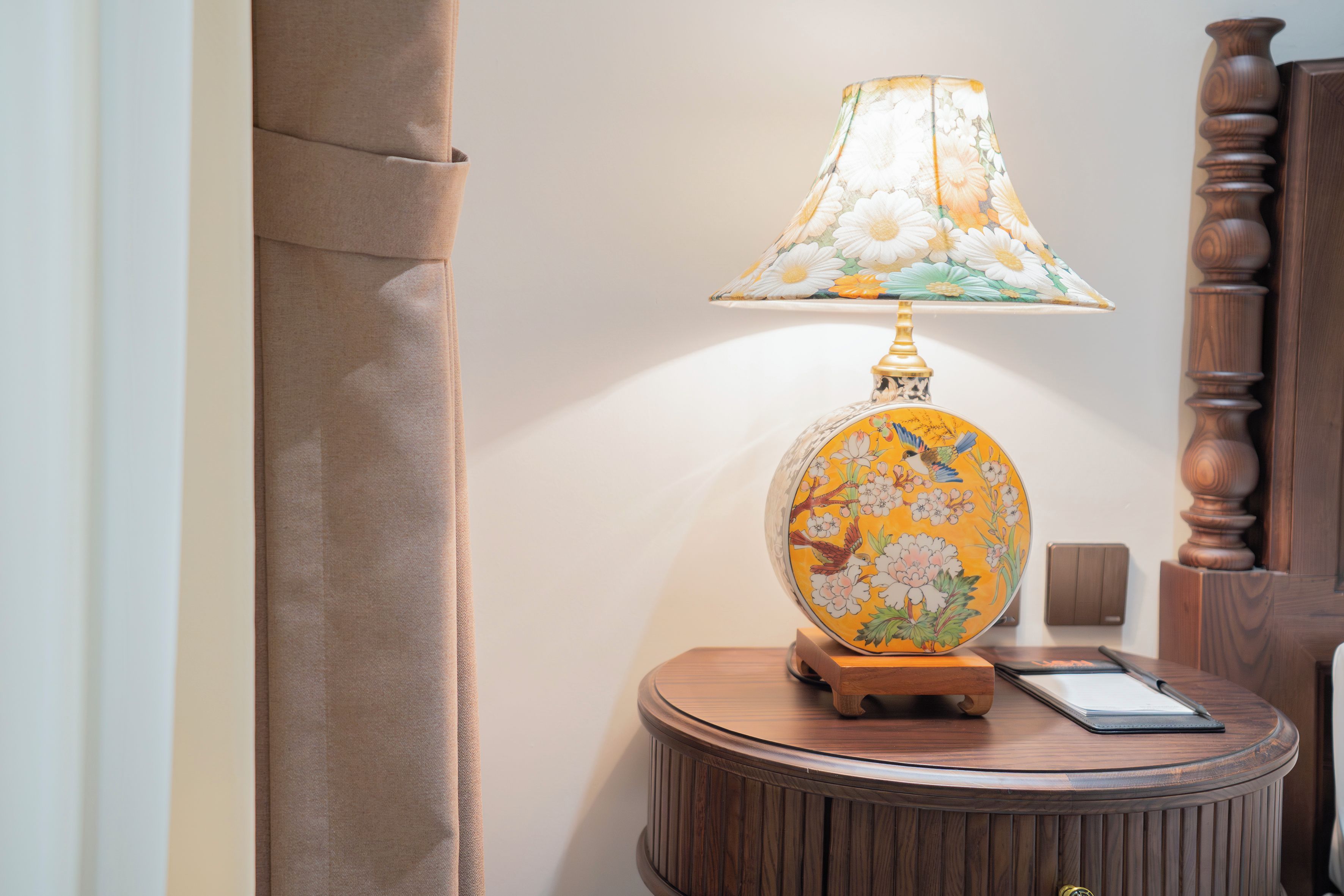 Une table ronde en bois, sur laquelle se trouvent une lampe et un bloc-notes.