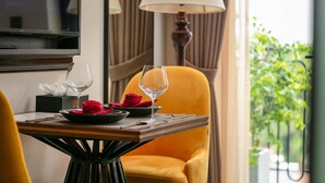 A dining table with a wine glass, a red rose, and a black bowl. A lamp is on the table, and curtains are in the background. - Westlake Lion Boutique Studio & Spa (Hanoi)