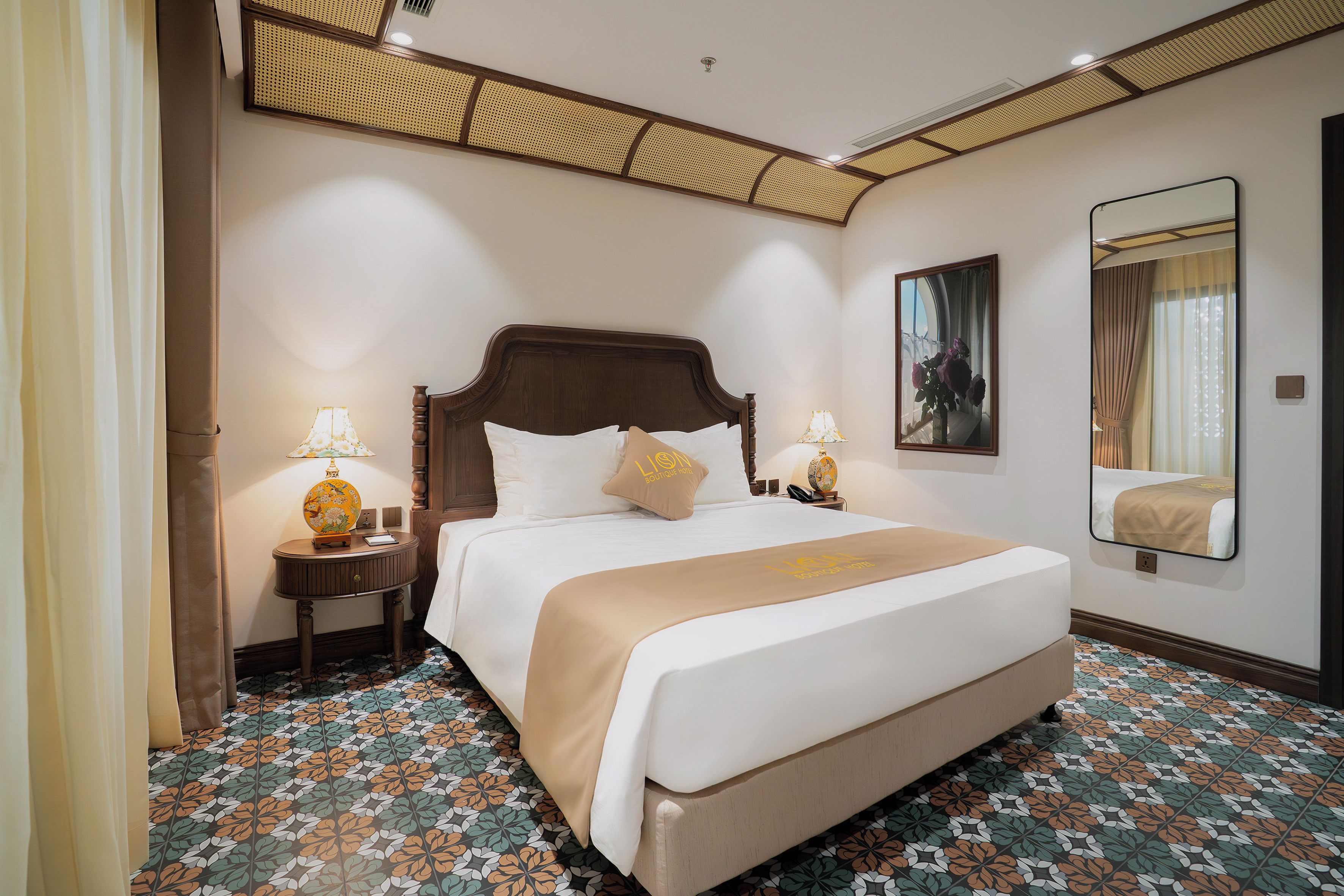 A hotel room with a large bed, two bedside tables with lamps, a mirror, and a floral-patterned floor.