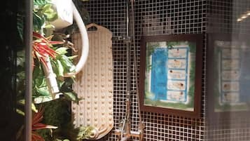 A shower area with a wooden basin, a white showerhead, and a tiled wall.