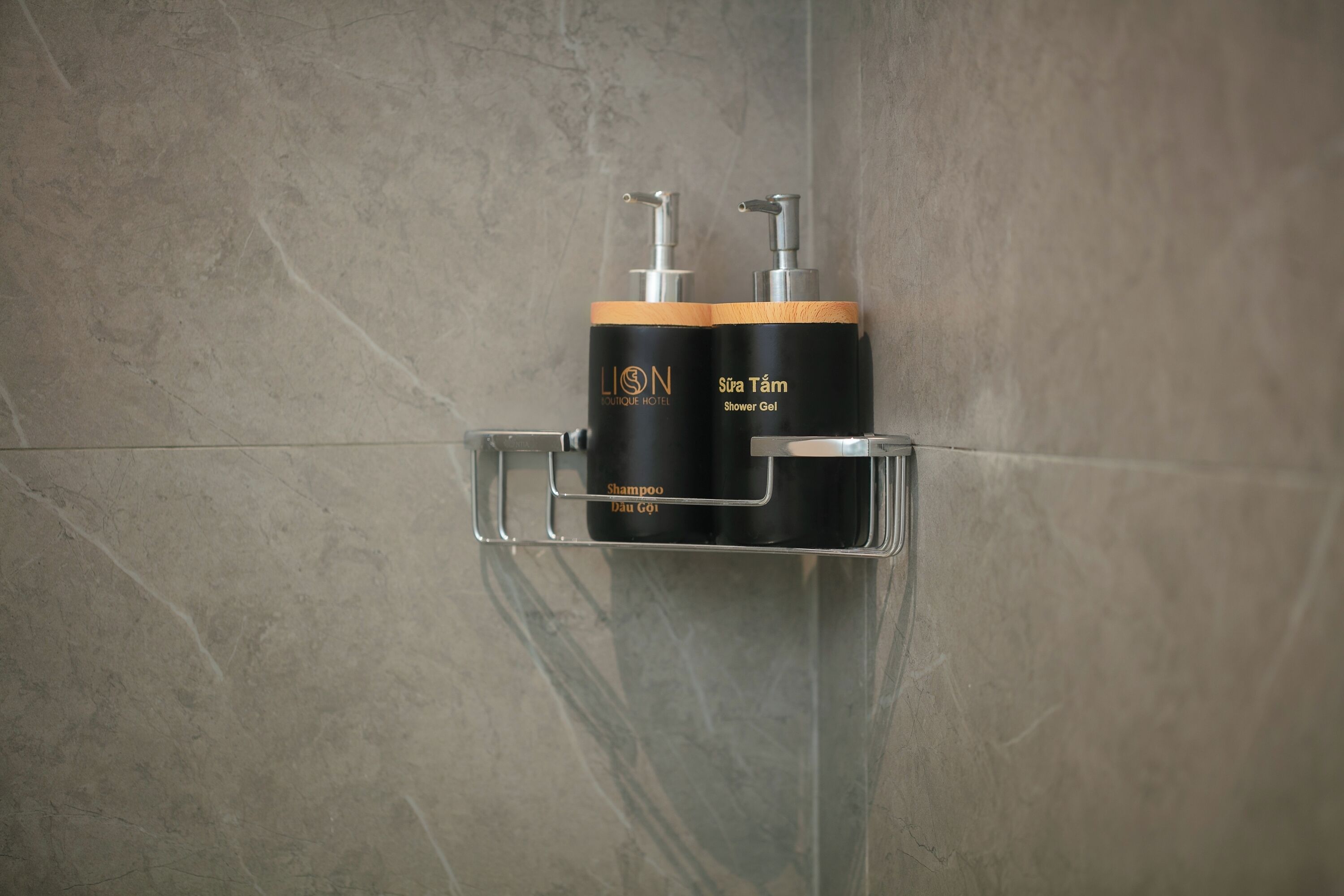 Une salle de bain avec un distributeur de gel douche et de shampoing fixé sur une étagère murale.