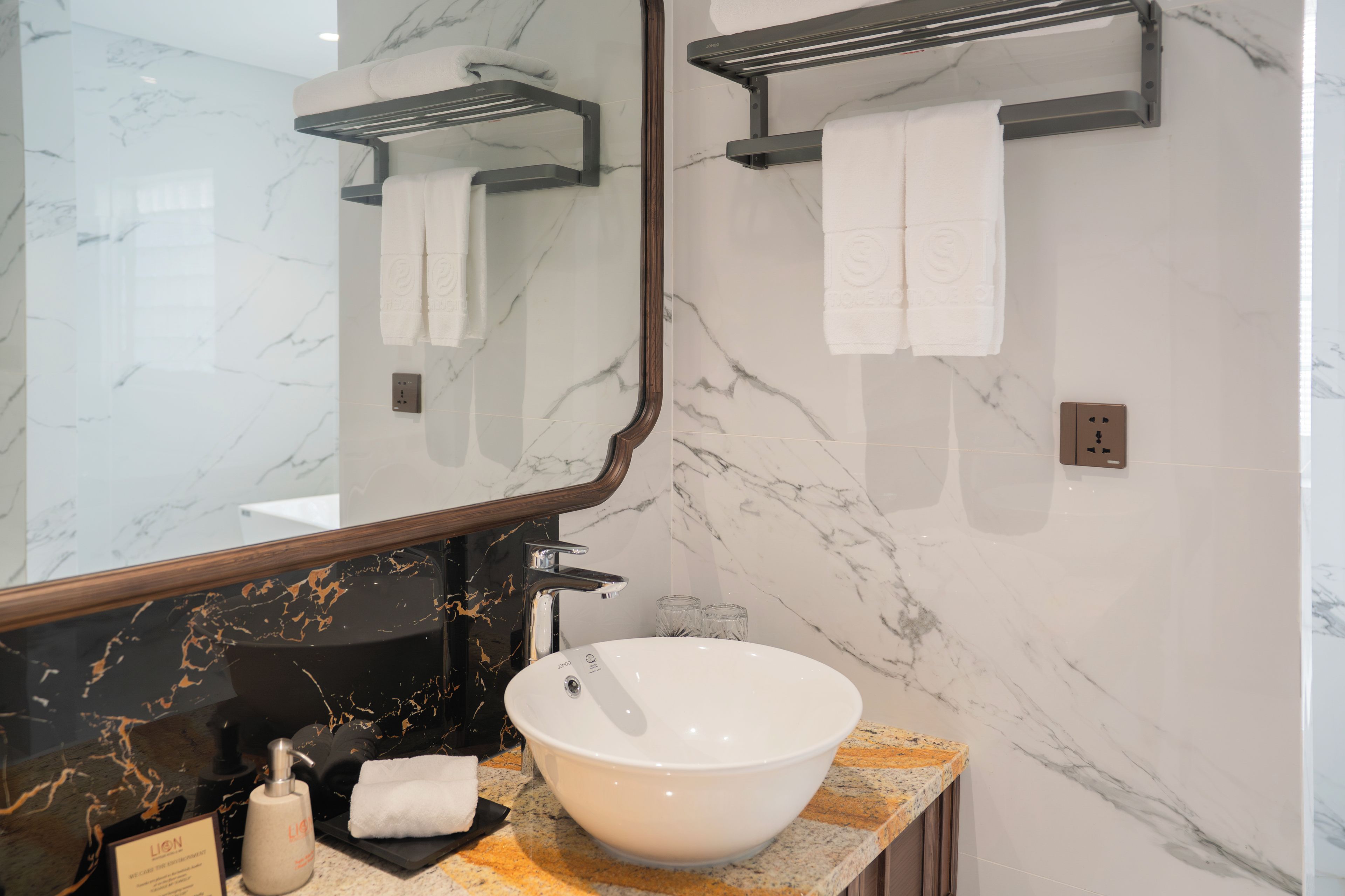 A bathroom with a large mirror, a white sink, and two towel racks.