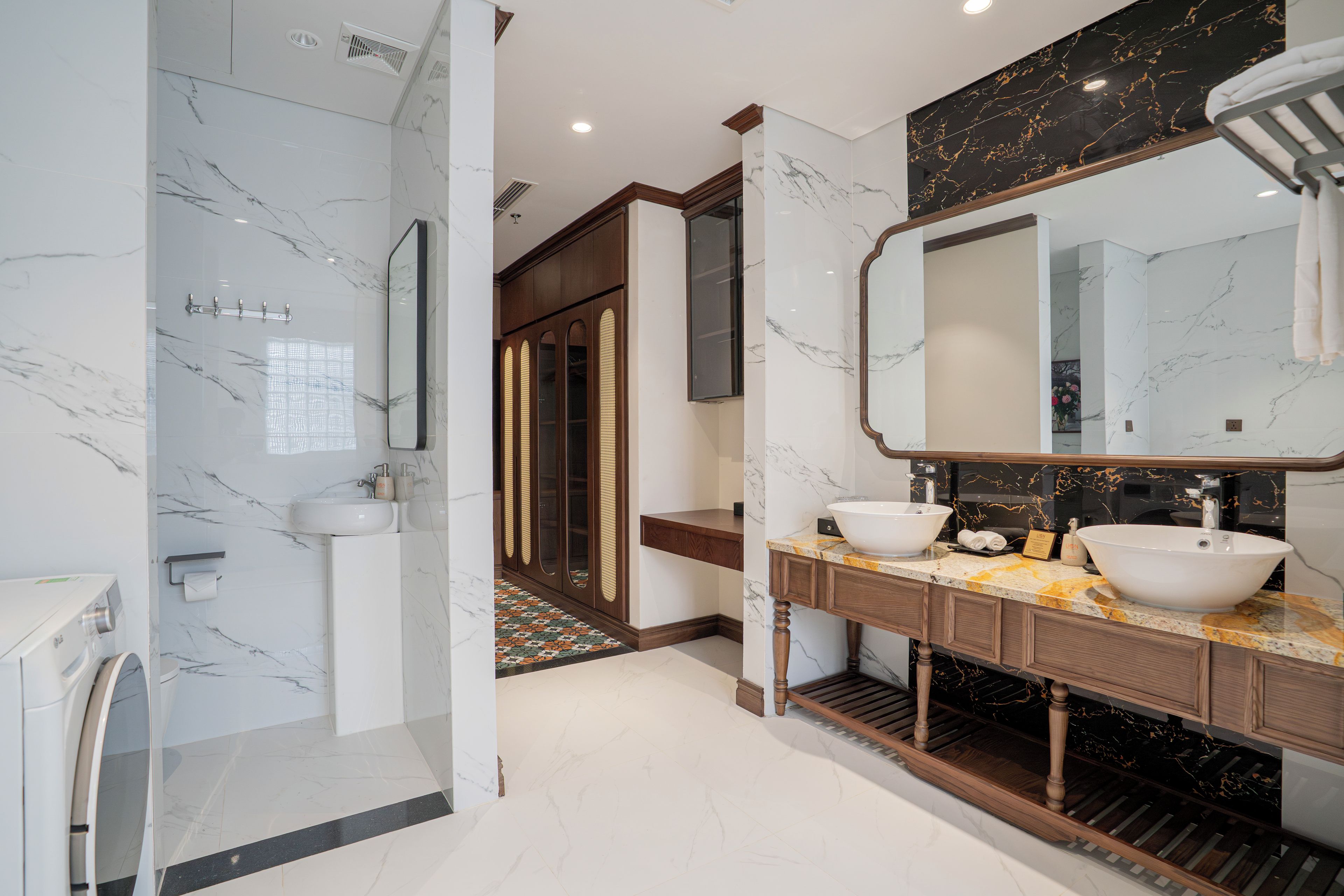 Un baño moderno con ducha a nivel, dos lavamanos y un espejo grande.