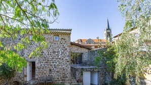 Un bâtiment en pierre avec un petit porche, un garage et un chemin pavé de pierres.