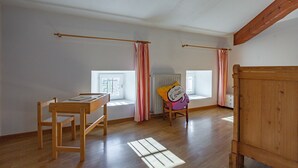 Une pièce avec une table en bois, une chaise, une fenêtre avec des rideaux et un radiateur.