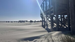 Un muelle de madera que se adentra en una playa arenosa bajo un cielo despejado.