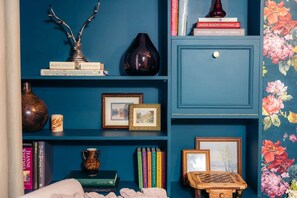 Una estantería con libros, un florero y cuadros enmarcados.