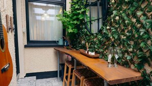 A wooden table with benches, a window, and a wall covered in green foliage.