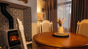 A dining area with a round wooden table, white chairs, a decorative vase, and a fireplace.