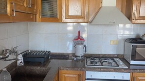 A kitchen with wooden cabinets, a granite countertop, a stainless steel range hood, a gas stove, an oven, and a microwave. - Apartment in the heart of hazmieh (Hazmieh)