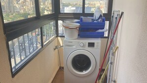 A laundry room with a washing machine, a blue gas cylinder, and cleaning supplies. - Apartment in the heart of hazmieh (Hazmieh)
