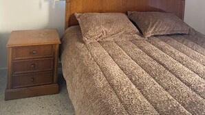A bedroom with a wooden bed, a nightstand, and a window with horizontal blinds. - Apartment in the heart of hazmieh (Hazmieh)