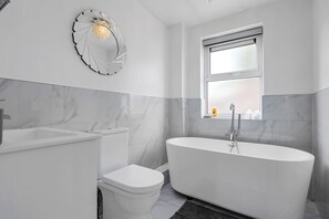 A modern bathroom with a freestanding bathtub, a toilet, and a sink.