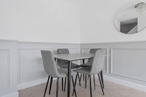A dining area with a rectangular table and four grey upholstered chairs with black legs.