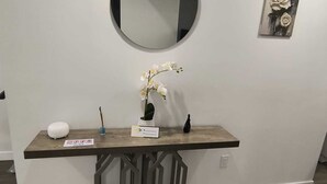 A reception desk with a round mirror, a small potted plant, and a framed artwork on the wall.