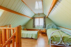 Une chambre de dortoir avec deux lits, des meubles en bois, une fenêtre avec des rideaux et un plafond en pente.