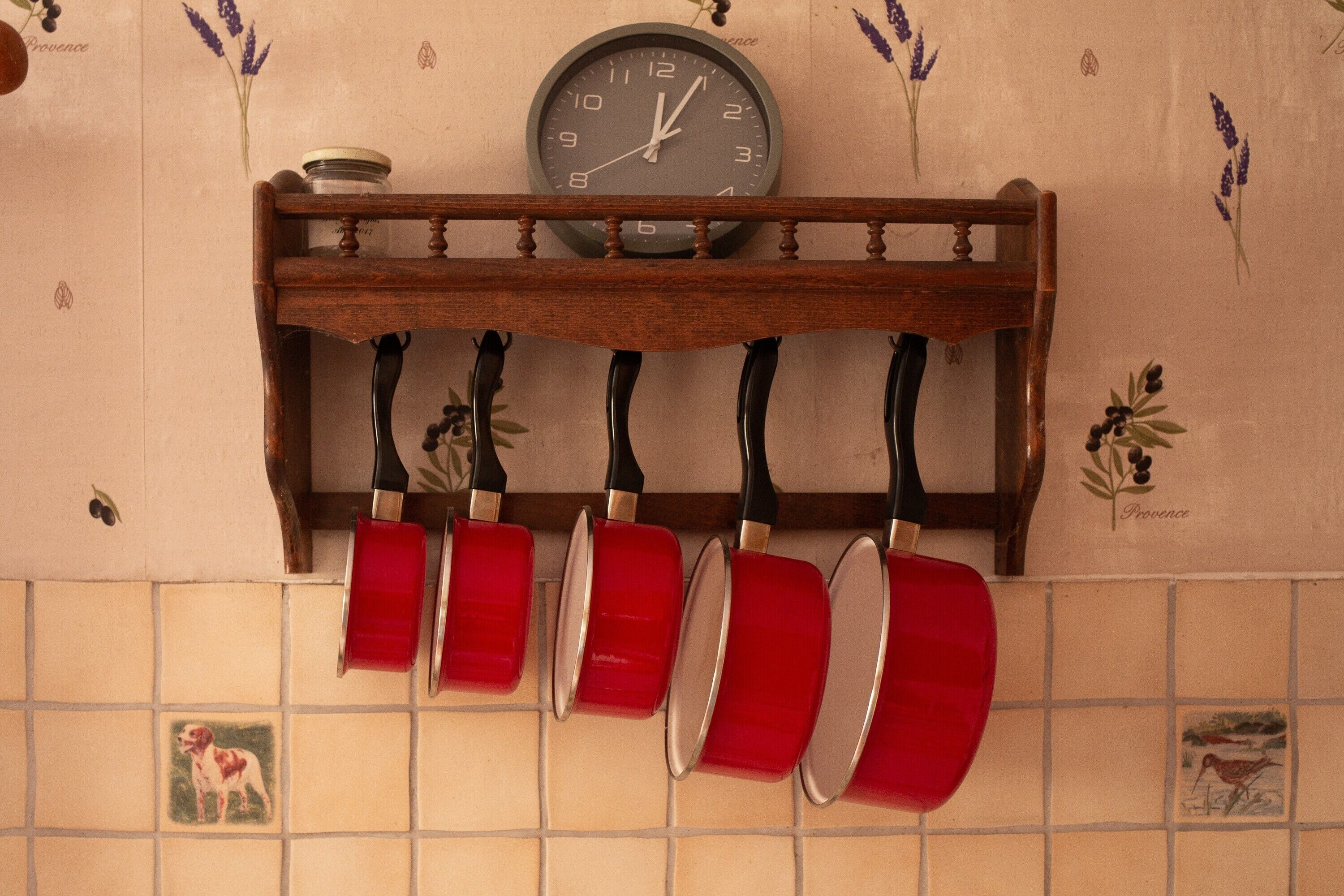 Una cocina con un reloj, ollas colgantes y azulejos decorativos.