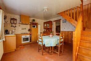 Une cuisine avec des meubles en bois, une table à manger avec des chaises, un four à micro-ondes et un escalier.