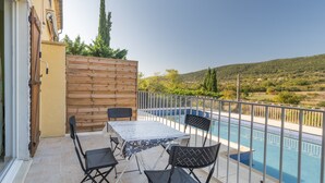 A balcony with a pool, outdoor seating, and a view of the countryside.