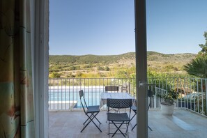 A balcony with a pool, outdoor seating, and a view of a hilly landscape. - Magnificent Accommodation in Southern Ardèche with Peaks (Lagorce)