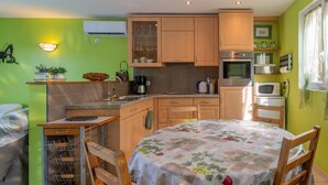 A compact kitchen with wooden cabinets, a dining table with a floral tablecloth, and a small breakfast bar.