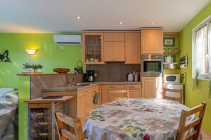 Une cuisine compacte avec des meubles en bois, une table à manger recouverte d’une nappe à motifs floraux et un petit comptoir pour prendre le petit-déjeuner.