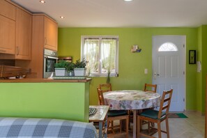 A kitchen with wooden cabinets, a stove, and a dining area with a table and chairs. - Beautiful Estate in the South of Ardèche with Large Pool, BBQ, and Games (Lagorce)