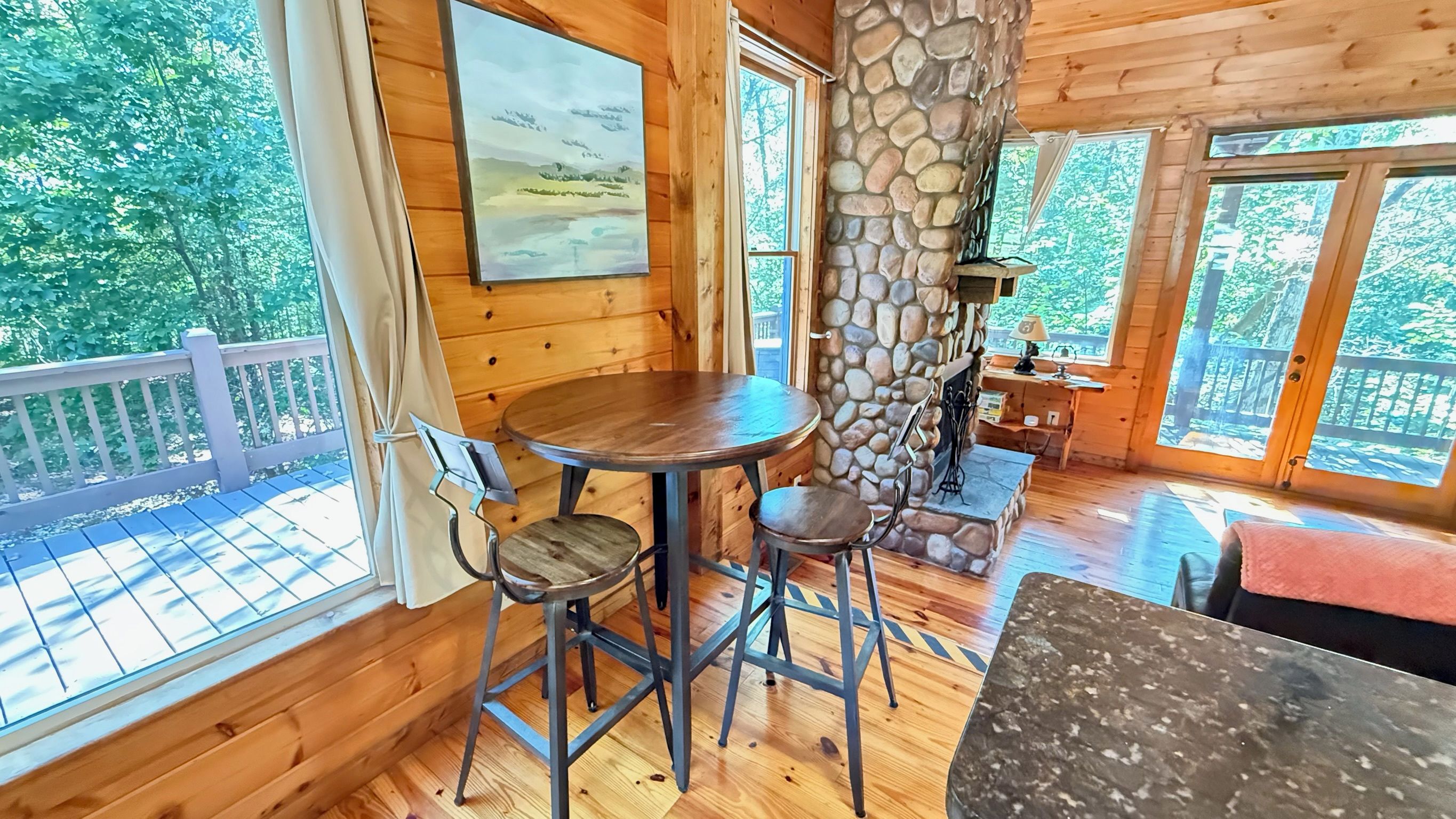 A wooden interior with a stone fireplace, a round table, and two chairs.