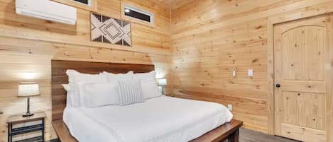Een slaapkamer met houten lambrisering, een bed, nachtkastjes en een deur.