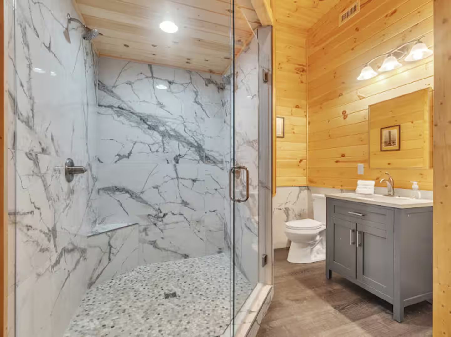 A bathroom with a glass-enclosed shower, marble walls, and wooden paneling.