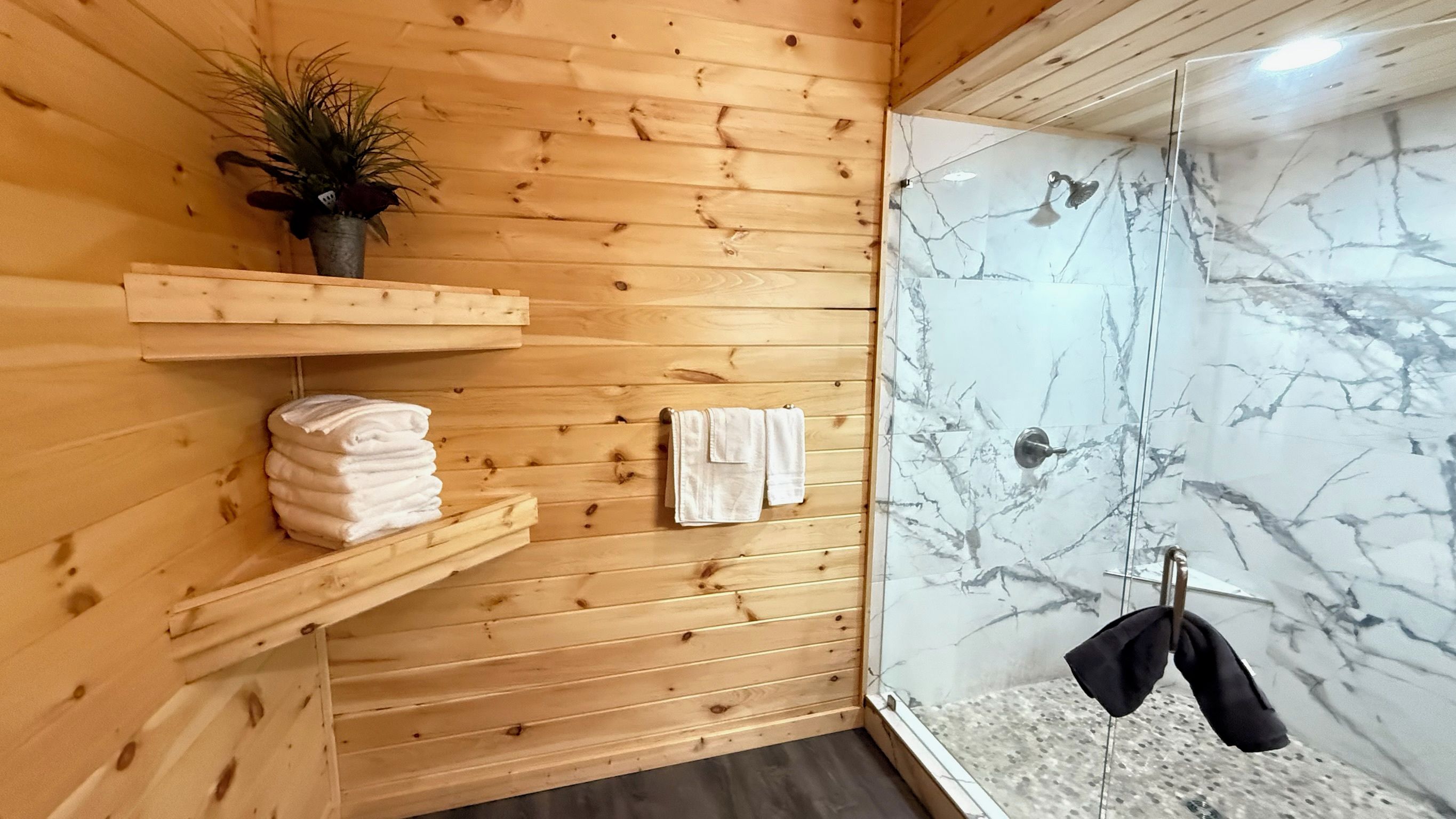 A wooden interior with a shower area featuring marble walls.