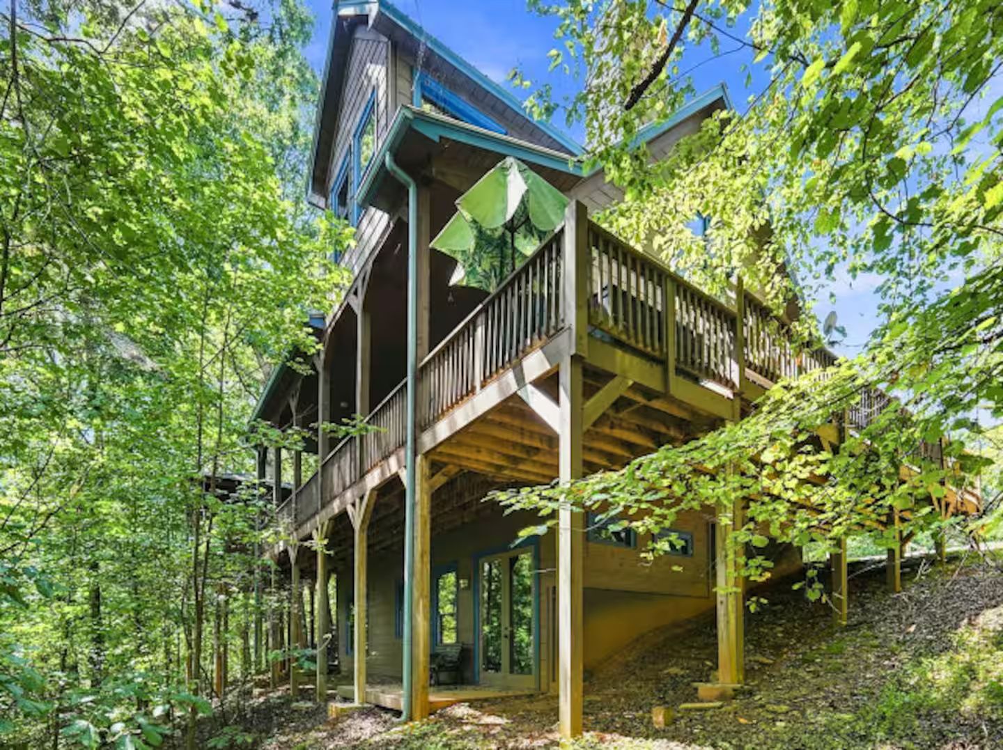 A wooden cabin with a balcony, surrounded by trees.