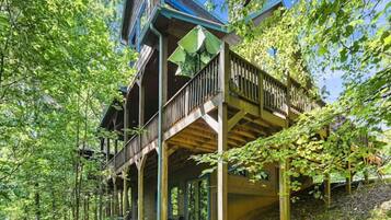 A wooden cabin with a balcony, surrounded by trees.
