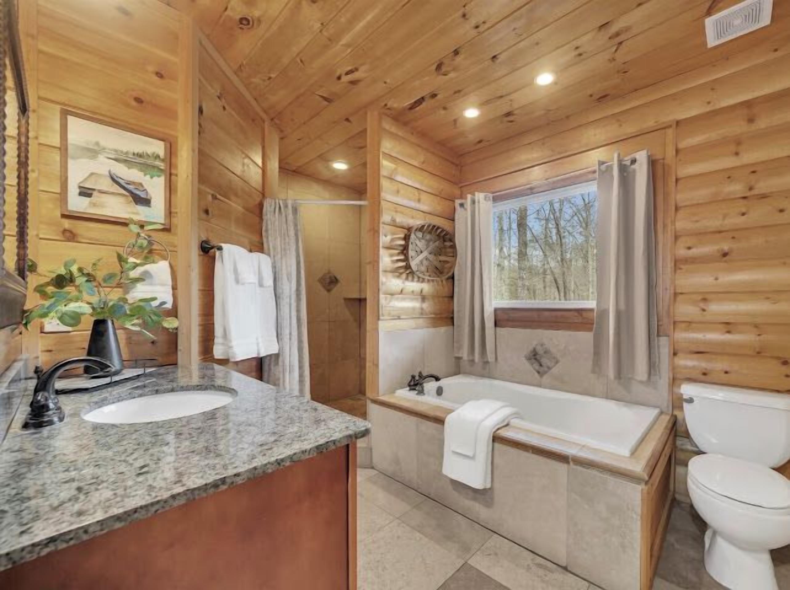 Ein Badezimmer einer Holzhütte mit Waschbecken, Badewanne und Toilette.