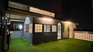 Un edificio con un espacio exterior techado, un patio cercado y un pequeño jardín.