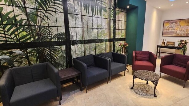 A seating area with sofas and a coffee table, a large window with a view of greenery, and a painting on the wall.