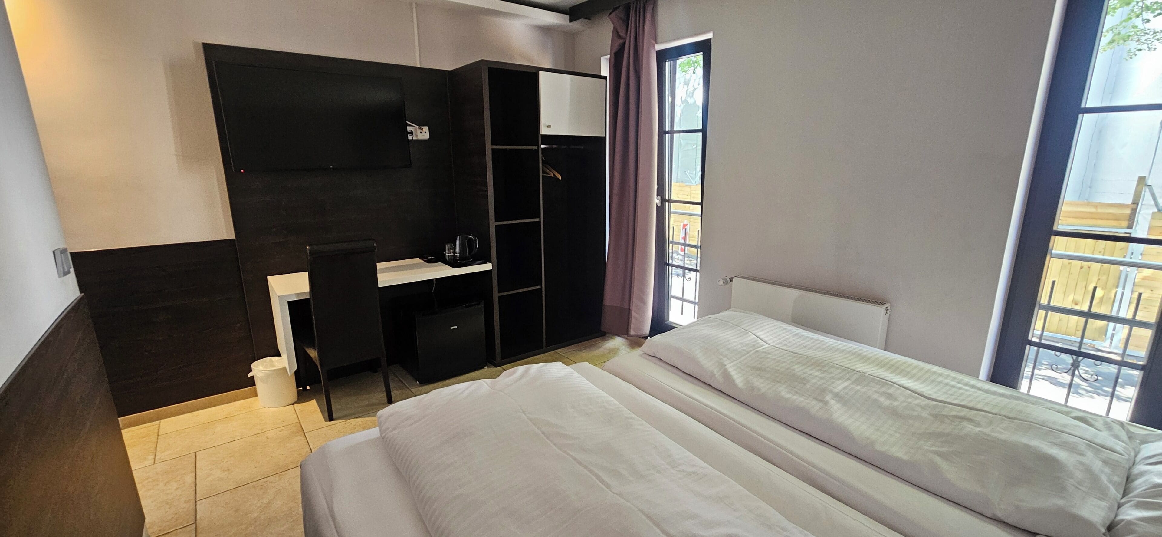 Un dormitorio con cama, escritorio, armario y ventana.