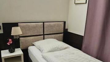 A single bed with a headboard, a bedside table with a lamp, and a picture on the wall.