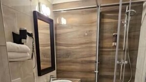 A bathroom with a toilet, sink, mirror, and shower.