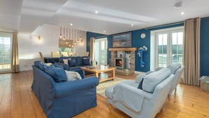 A spacious living room with a fireplace, blue walls, and large windows.