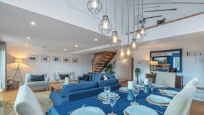 A dining area with a blue tablecloth, white plates, and a chandelier.